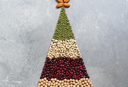Christmas tree of different beans, chickpeas and almonds on a gray rustic background. The concept of holiday and vegetarian food. Top view, flat lay, copy space